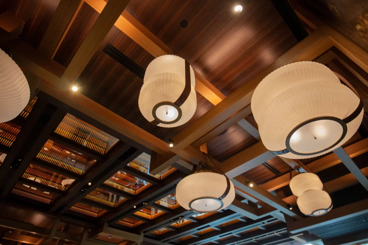 A stylish wooden ceiling with intricate lantern-style hanging lights, creating a warm and inviting ambiance in a modern interior space.