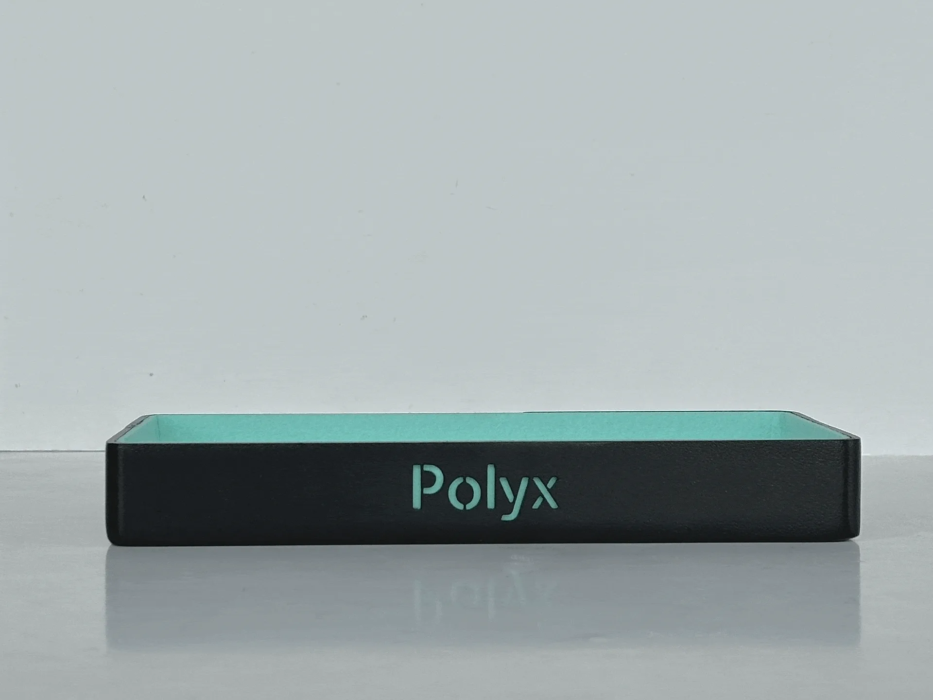 A black and turquoise box with the word "Polyx" displayed on the front against a neutral background.