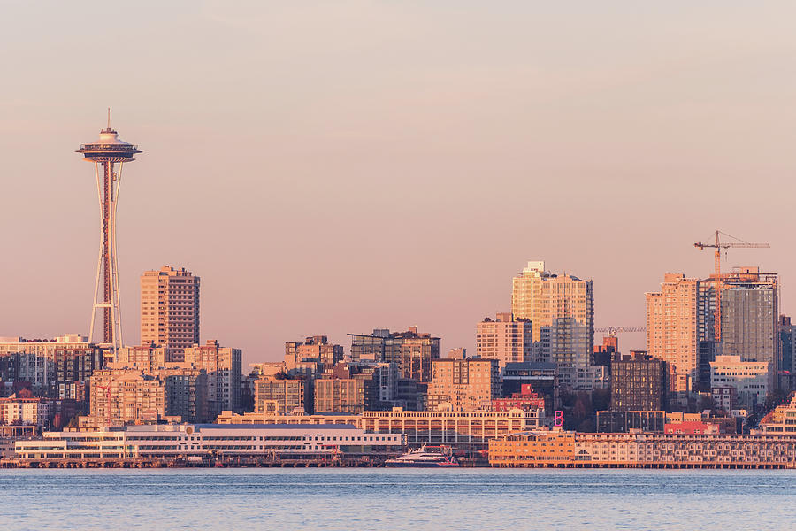A cityscape of Seattle at sunset featuring the iconic Space Needle, with downtown buildings and waterfront in the foreground.