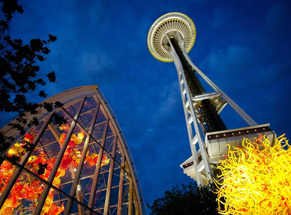 A night view of the Space Needle in Seattle with illuminated glass sculptures from the Chihuly Garden and Glass exhibit.