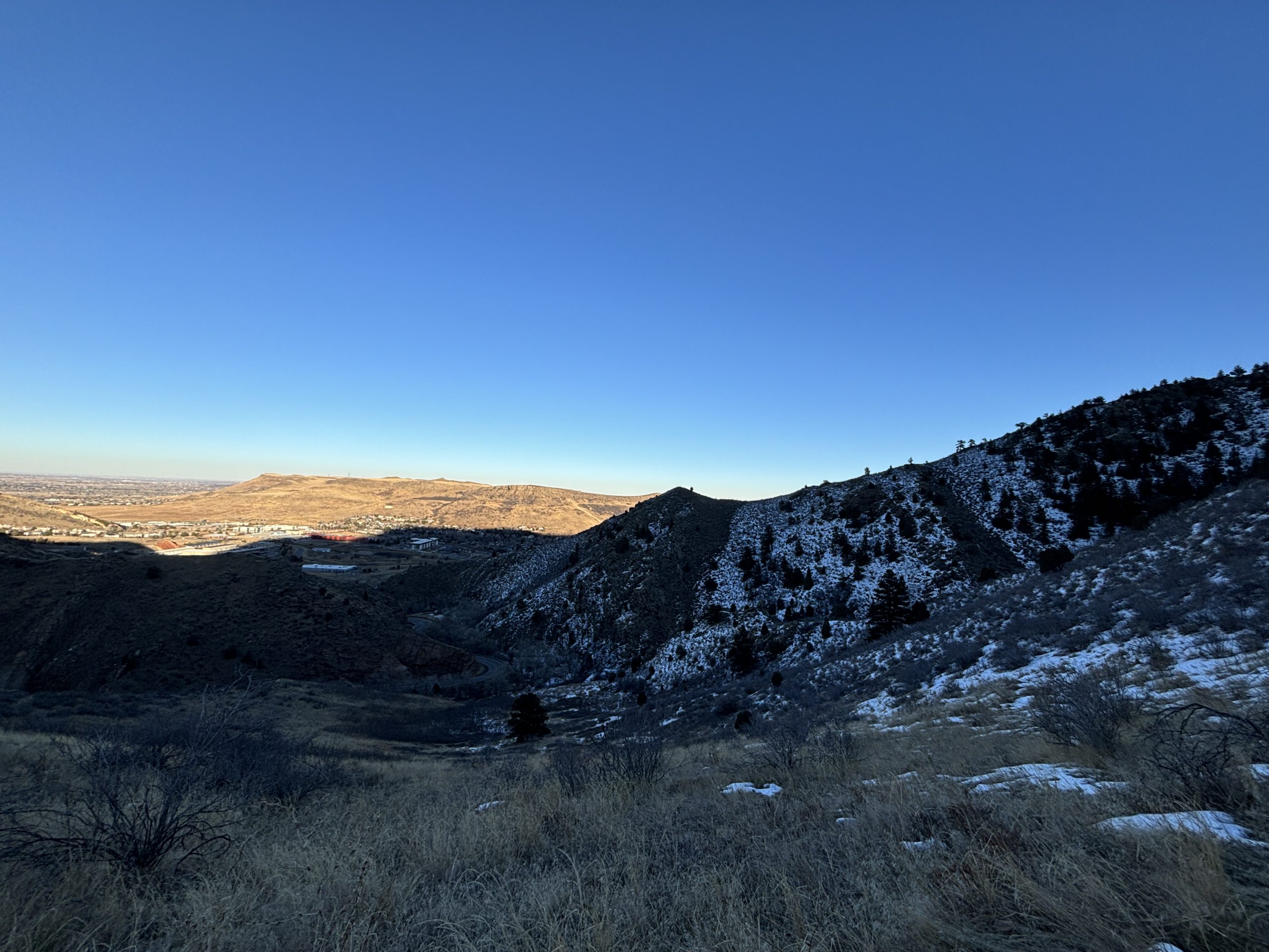 A scenic landscape with snow-dusted hills and blue sky, showing the vast expanse of terrain under sunlight.