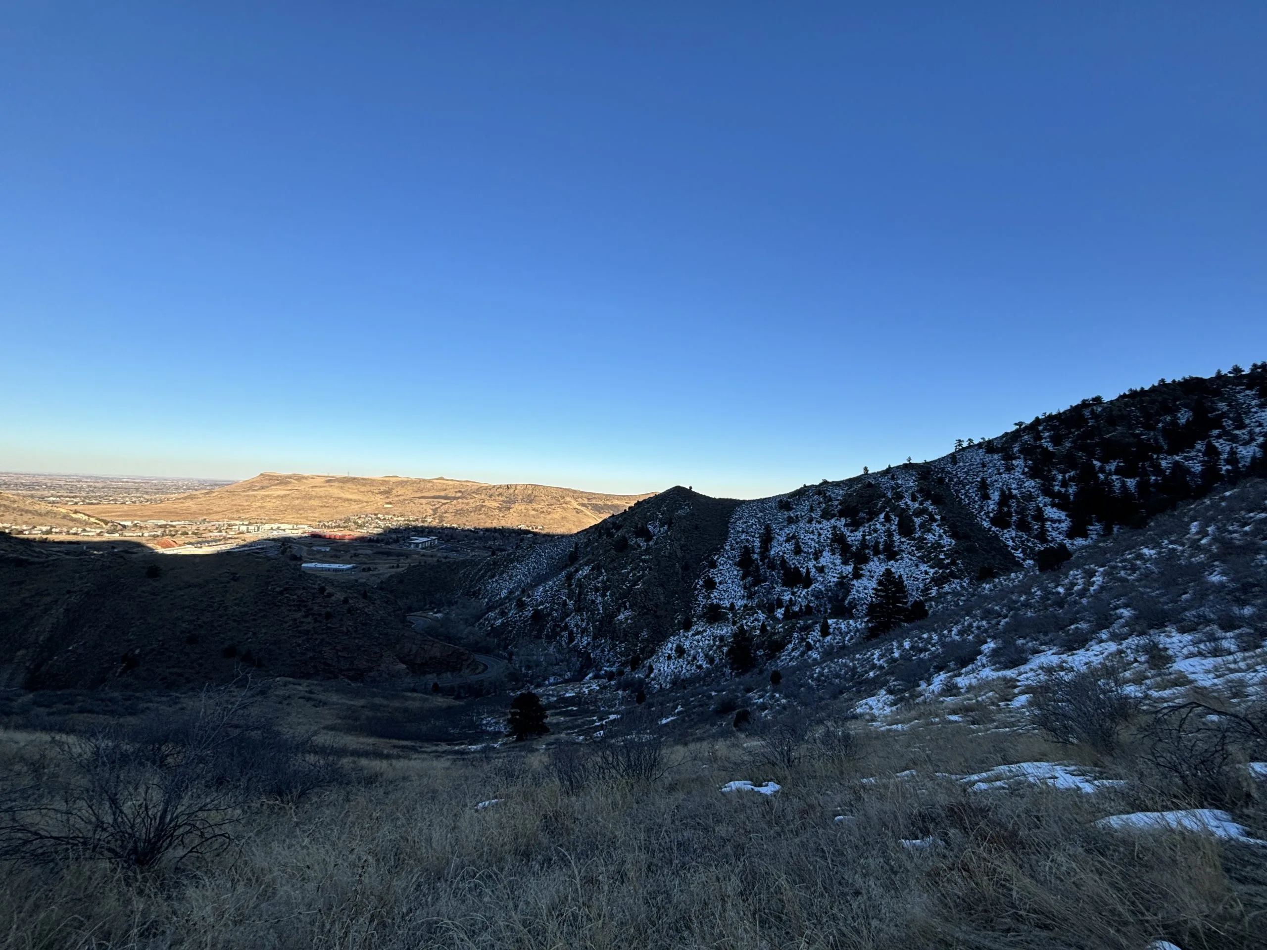 A scenic landscape with snow-dusted hills and blue sky, showing the vast expanse of terrain under sunlight.